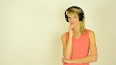 Genç çekici kadın kulaklık ile müzik dinler ve kadın düşünme - studio (fotoğraf makinesi içine bakmak)