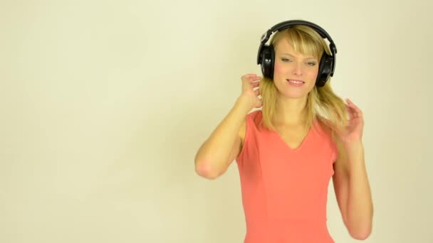 Young attractive woman listens to music with headphones and plays with hair - studio — Stock Video