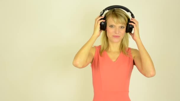 Молода приваблива жінка слухає музику з навушниками - жінка знімає навушники студія — стокове відео