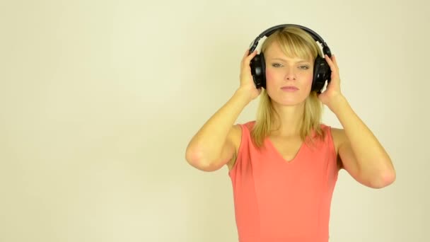 Joven mujer atractiva escucha música con auriculares - horrible música- estudio — Vídeos de Stock