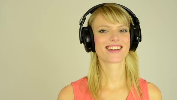 Mujer atractiva joven escucha música con auriculares y baile - estudio - primer plano — Vídeo de stock