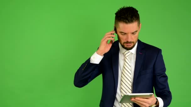 Ο άνθρωπος των επιχειρήσεων στο τηλέφωνο και λειτουργεί σε tablet - πράσινη οθόνη - στούντιο — Αρχείο Βίντεο