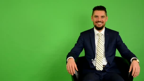 Business människa sitter och ler - grön skärm - studio — Stockvideo