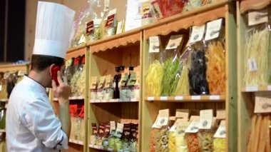 Raf - Dükkanı torbalarda renkli makarna (zeytin yağı, unu vb.) önünde Şef telefon