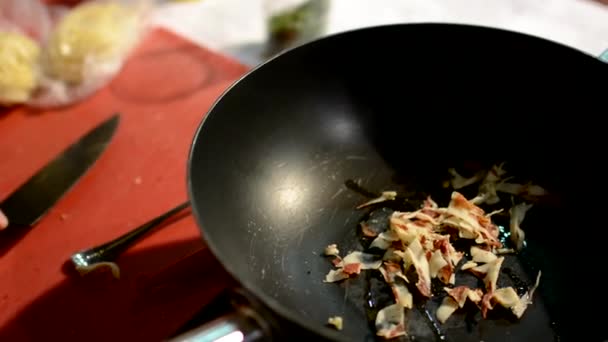 Шеф-повар нарезает бекон и добавляет в сковородку траву — стоковое видео