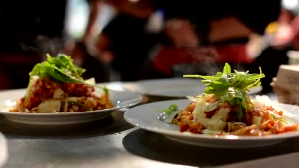 Питание (еда: макароны) готовое к подаче - официанты на заднем плане - пар из продуктов питания — стоковое видео