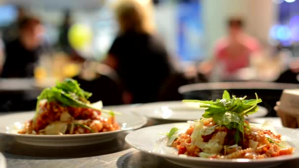 Comidas (comida: pasta) listas para servir - el camarero lleva las comidas a los clientes - gente de fondo - vapor de la comida — Vídeo de stock