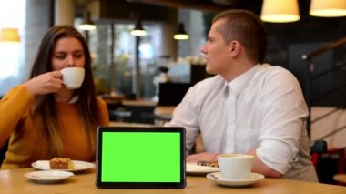 Tablet yeşil ekran - mutlu çift konuşmak, yemek ve içmek kafede - kahve ve kek