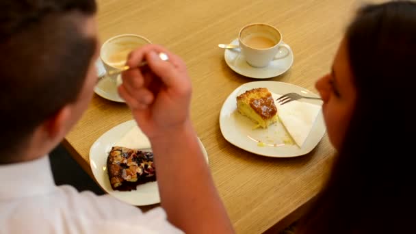 Pareja feliz comer pastel y beber café en la cafetería — Vídeos de Stock