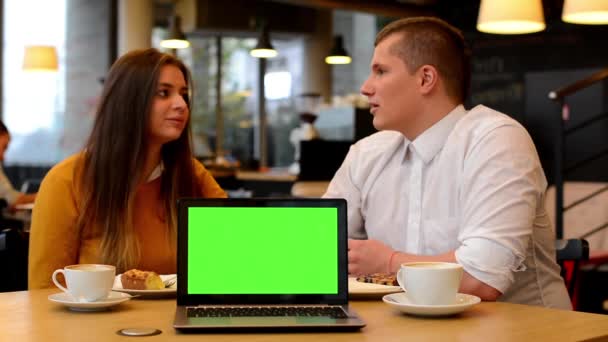 Computer green screen - happy couple smiles to camera and point at notebook in cafe - coffee and cake — Stock Video