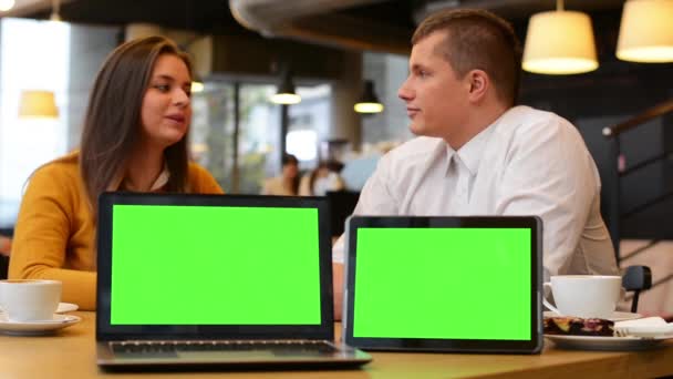 Počítač (notebook) a tablet zelené obrazovky - šťastný pár úsměvů na kameru v café - káva a dort