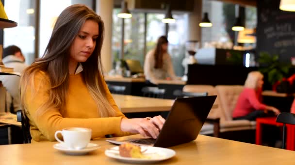 Mulher trabalha no computador (caderno) em café - café e bolo — Vídeo de Stock