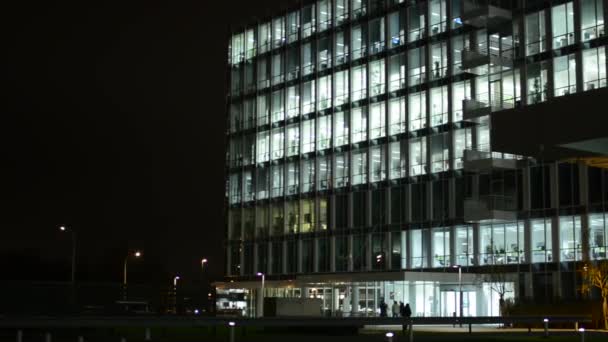 Edificio de negocios (oficinas) - noche - ventanas con luces - personas — Vídeo de stock