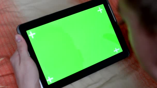 Человек лежит в постели и работает на планшете - зеленый экран — стоковое видео