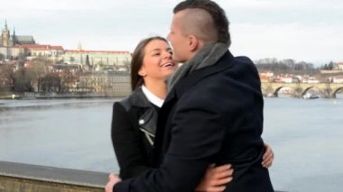Mutlu çift (kucaklama) selamlıyorum ve köprü - şehir (Prag) arka planda (konuşma) konuşmak