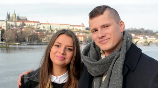 Joven feliz pareja sonrisa en el puente - ciudad (Praga) en el fondo - primer plano — Vídeo de stock