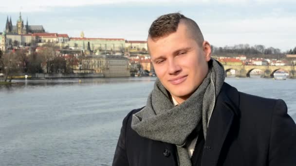 Young handsome man smiles - bridge - city (Prague) in background - closeup — Stock Video