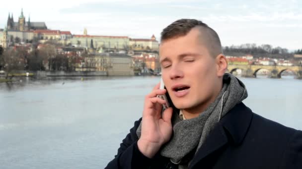 Jovem bonito homem telefone na ponte - cidade (Praga) no fundo — Vídeo de Stock