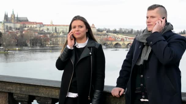 Un par de teléfono en el puente - teléfono hombre y teléfono mujer - ciudad (Praga) en segundo plano — Vídeos de Stock