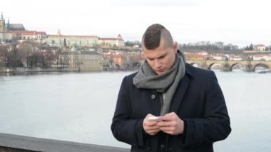 Adam akıllı telefon ve kamera köprüde - şehir (Prag) arka planda esirgemezdin çalışır