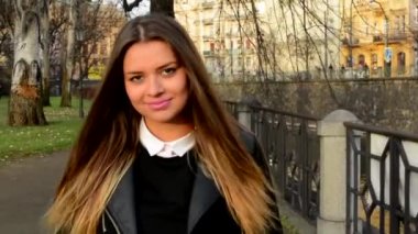 Genç çekici kadın yürüyerek şehir ve gülümser kamera - portre