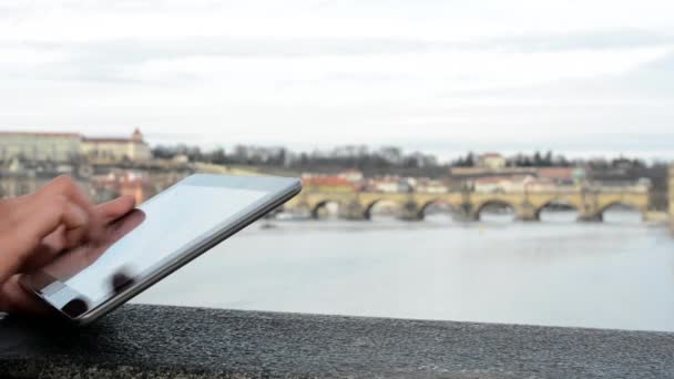Mulher trabalha em tablet na ponte - cidade (Praga) e rio no fundo - close-up (tiro na mão ) — Vídeo de Stock