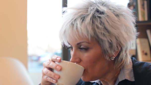 Ділова жінка середнього віку п'є каву крупним планом (роздрібна торгівля) з боку — стокове відео
