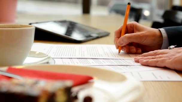 Mujer de mediana edad firma un contrato (firma) en la cafetería - café con pastel y tableta — Vídeo de stock