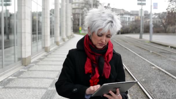 Mulher de meia-idade trabalha em tablet - rua urbana com carros na cidade — Vídeo de Stock