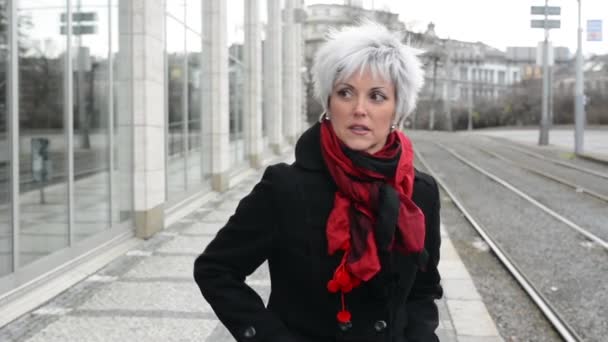 Middle aged woman waits on urban street with cars in the city — Stock Video