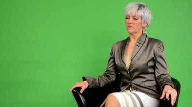 Yaşlı kadın oturup gider ve gülümsüyor iş orta - yeşil ekran - stüdyo