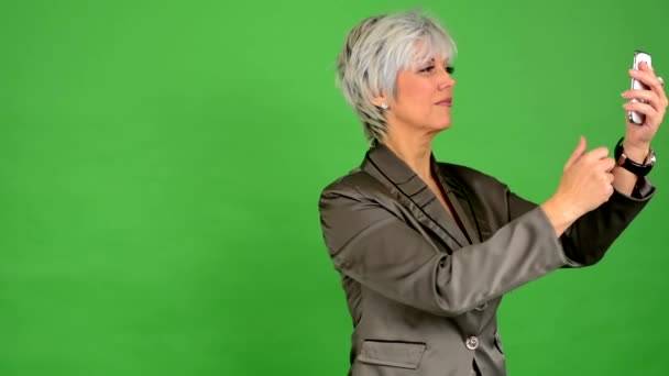 Bedrijfsleven midden leeftijd vrouw foto's met telefoon (smartphone) - groen scherm - studio — Stockvideo