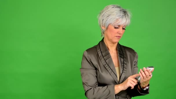 Empresa mujer de mediana edad trabaja en el teléfono inteligente - pantalla verde - estudio — Vídeo de stock