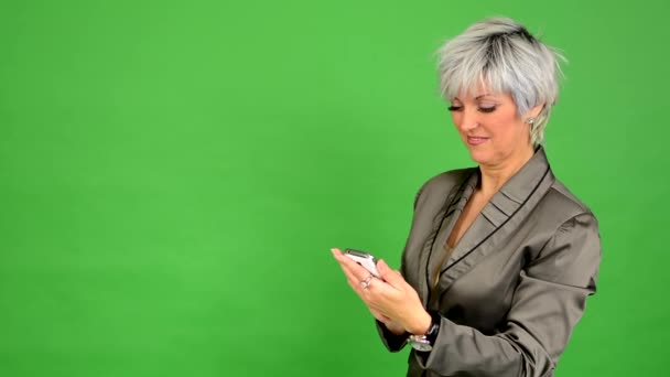 Empresa mujer de mediana edad trabaja en el teléfono y sonríe - pantalla verde - estudio — Vídeo de stock