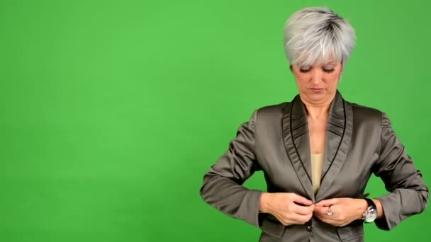 Firmy średniej wieku kobieta dostosowuje odzież - zielony ekran - studio - zbliżenie — Wideo stockowe