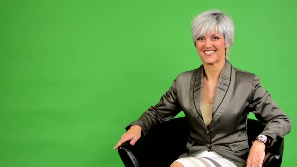 Business middle aged woman sits and smiles - green screen - studio — Stock Video