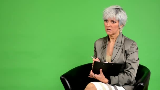 Femme d'âge moyen d'affaires s'assoit et écrit sur papier et sourit - écran vert - studio — Video