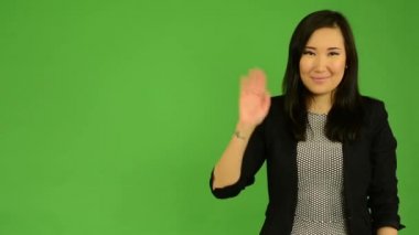 El - yeşil ekran studio ile genç çekici Asyalı kadın dalgalar