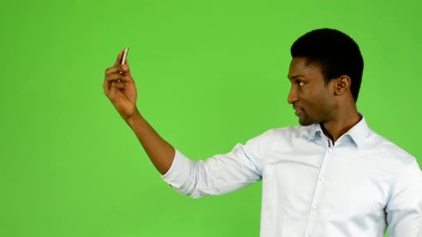 Joven hombre negro guapo fotografías con teléfono inteligente (selfie) - pantalla verde - estudio — Vídeo de stock