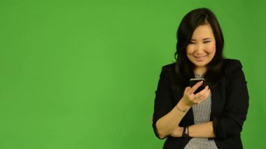 Genç çekici Asyalı kadın inşaat üstünde smartphone ve gülümser - yeşil ekran stüdyo