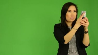 Smartphone - yeşil ekran studio ile genç çekici Asyalı kadın fotoğrafları
