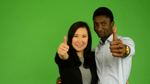 Feliz pareja mostrar pulgar en acuerdo - negro hombre y asiático mujer - verde pantalla estudio — Vídeo de stock