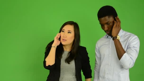 Feliz pareja teléfono - hombre negro y mujer asiática - estudio de pantalla verde — Vídeo de stock