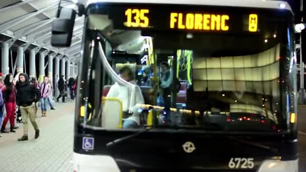 Bus station mensen wachten en krijgen op het bus - wegnaar auto's - nacht stad - timelapse — Stockvideo