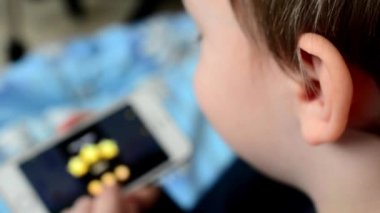 Küçük çocuk oyunlarını omzunun üzerinden vurdu Smartphone-