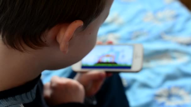 Kleine jongen speelt games op de smartphone - schot over de schouder — Stockvideo