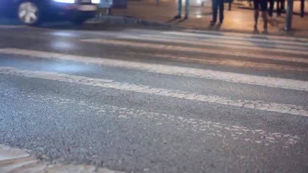 Calle urbana con coches - la gente cruza la calle - paso peatonal - sombras de personas - noche - primer plano en las piernas — Vídeos de Stock