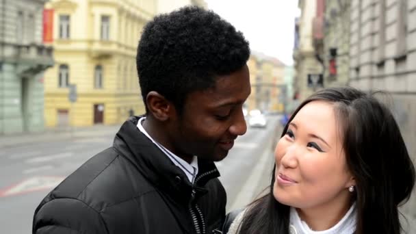 Feliz pareja sonrisa a la cámara - hombre negro y mujer asiática - calle urbana con coche - primer plano — Vídeo de stock