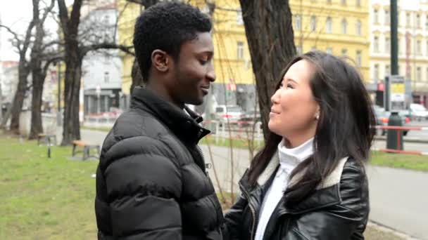 Happy couple embrace and talk (conversation) - black man and asian woman - urban street with cars - city — Stock Video