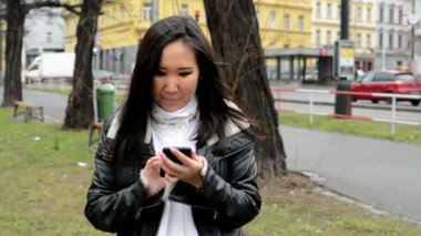 Genç çekici Asyalı kadın gülümser ve smartphone - araba ile kentsel sokak - şehir üzerinde çalışıyor